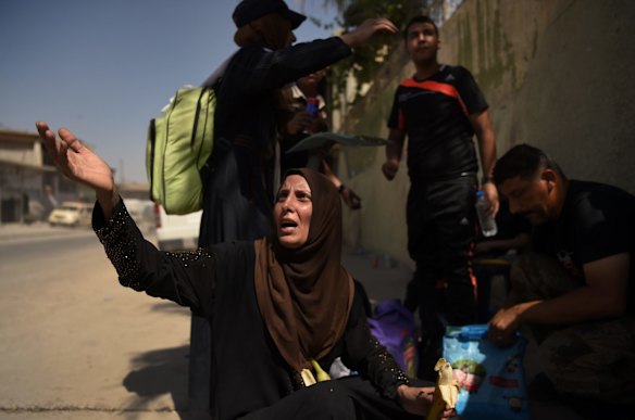 Families have their bags checked after arriving safely at a screening point after being rescued by Iraqi forces.