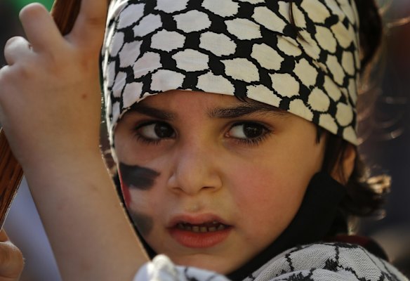 A Palestinian girl with the Palestinian headscarf or keffiyeh on her head, attends a protest in solidarity with Palestinians amid an escalating Israeli military campaign in Gaza, in the southern suburb of Beirut, Lebanon, Friday, May 14, 2021. Israeli defense forces have fired warning shots toward a group of people who crossed from Lebanon into Israeli territory during a protest.