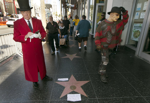 Gregg Donovan, left, who calls himself the unofficial ambassador of Hollywood, stands next to Bill Cosby's star on the Hollywood Walk Fame, tagged with a "Guilty on All 3 Counts!" in Los Angeles on Thursday.