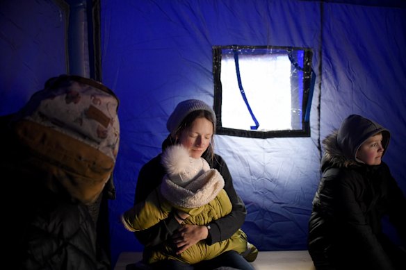 A refugee fleeing the conflict from neighbouring Ukraine holds her baby as she sits in a tent at the Romanian-Ukrainian border, in Siret, Romania.
