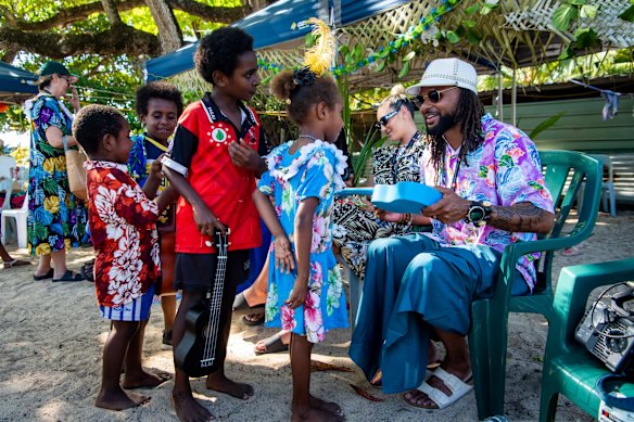 Basketballer Paddy Mills whose fore fathers are from Murray Islands signing ukeleles to children