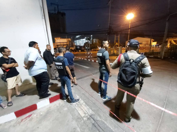 Police and bystanders stand near the scene of a shooting at the Terminal 21 mall, in Korat, Thailand.