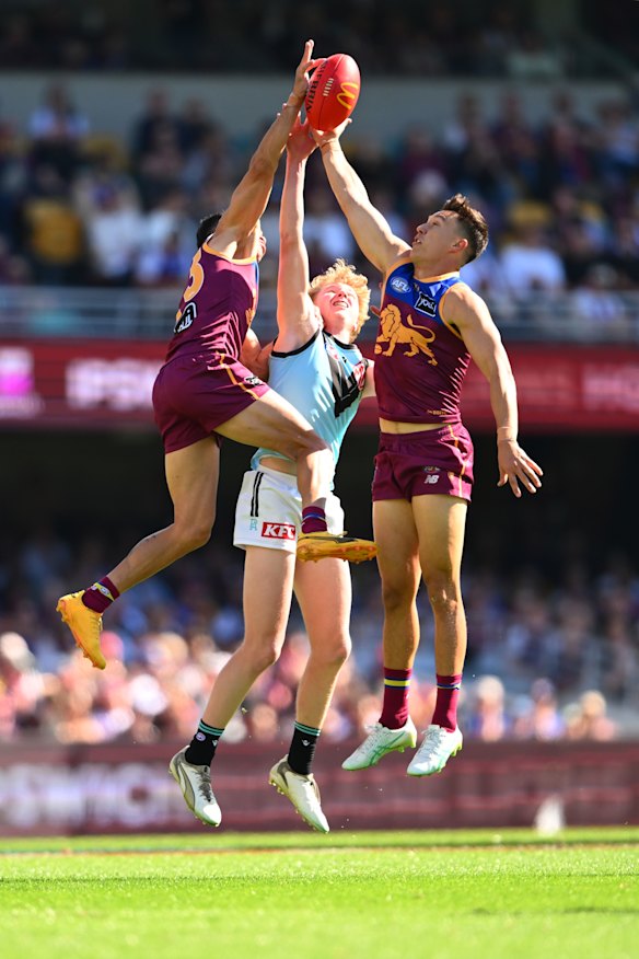 Balyn O’Brien of the Power competes for the ball against Charlie Cameron and Hugh McCluggage of the Lions.
