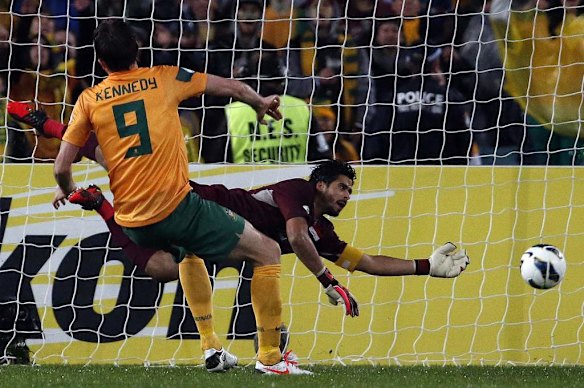 Australia's Josh Kennedy (L) scores a goal as Iraq's goalkeeper Noor Sabri dives during their World Cup qualifying game.