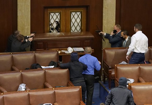Police officers point their guns at a door that was vandalised in the House Chamber during a joint session of Congress.