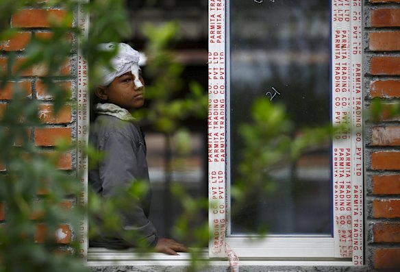 A boy injured in an earthquake looks out from the window of a hospital as bodies are brought in a day after the earthquake in Bhaktapur, Nepal April 26, 2015.