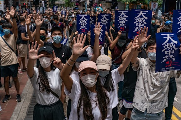 Pro-democracy supporters make gestures and hold placards as they take part in an anti-government rally.