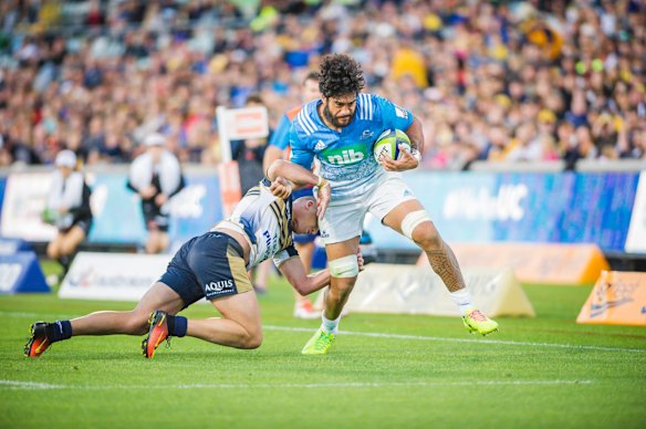 Brumbies fullback Tom Banks tries to stop a charging run by Blues' No.8 Akira Ioane.