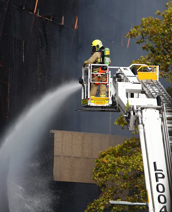 A firefighter pours water onto the burning construction site.
