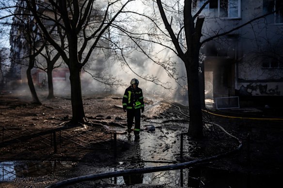 A firefighter walks through the scene of a suspected Russian missile attack on a high-rise apartment building in Kyiv, Ukraine, early Tuesday that killed at least four people and set the building ablaze.