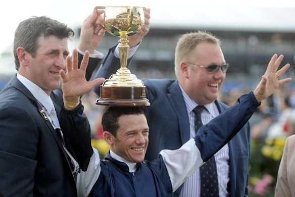 Trainer Robert Hickmott and Nick Williams with the cup over Brett Prebble's head.