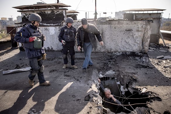 A resident shows de-miners the site of an empty rocket that struck the roof of a residential building as they clear the area in Kharkiv.