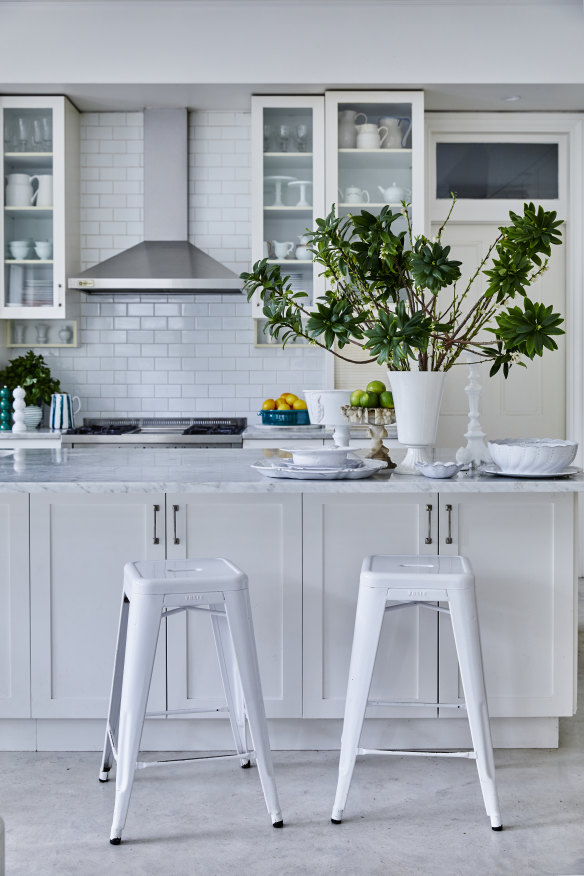 Ceramic tiles from Teranova line the back wall of the kitchen. Large glass cabinets hold French and Italian kitchenware, with more atop the marble island benchtop.