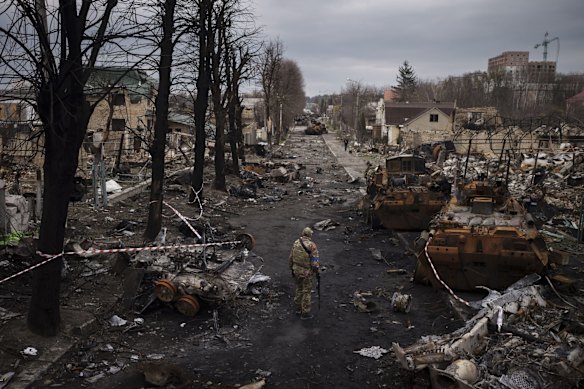 A Ukrainian serviceman walks past Russian tanks that were destroyed in Bucha.