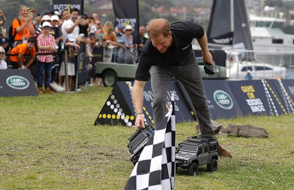 Britain's Prince Harry picks up a remote control car as he operates it at the Invictus Games driving challenge on Cockatoo Island in Sydney.