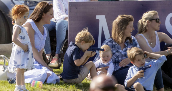 The Duchess of Cambridge, left, sits as Prince George plays with other unidentified spectators at a charity polo event.