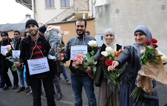 Muslims with placards reading "Islam is against terrorism" offer roses in the Sablons neighborhood of Le Mans, western France, on January 10, 2015,  in front of the mosque against which bullets were fired and 3 grenades launched on January 8. 