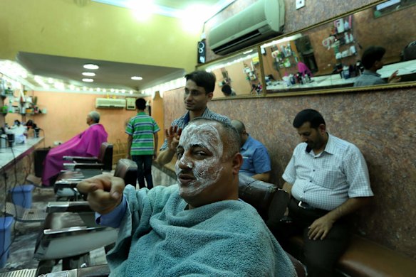 Iraqi army volunteer Asa'ad Matoori from Basra motions the pulling of a trigger when talking about wanting to kill Islamic State/ ISIS fighters as he recieves a facial scrub in a barber shop on Karada street in Karada area of Baghdad.