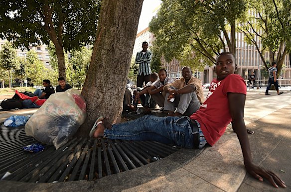 Sudanese refugees that were rescued by the Migrant Offshore Aid Station on board the MY Phoenix, now sit under a tree in the park area in front of Milan Central Station while they wait for money to be wired from Sudan so that they can make the next leg of their journey. 