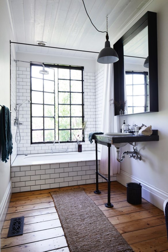 “I designed the basin stand, using industrial steel legs from a desk and reclaimed wood,” says Kali. A marble bath surround enhances the monochromatic decorating scheme.