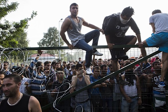 Refugees climb a border fence that separates Serbia from Hungary before violence broke out.