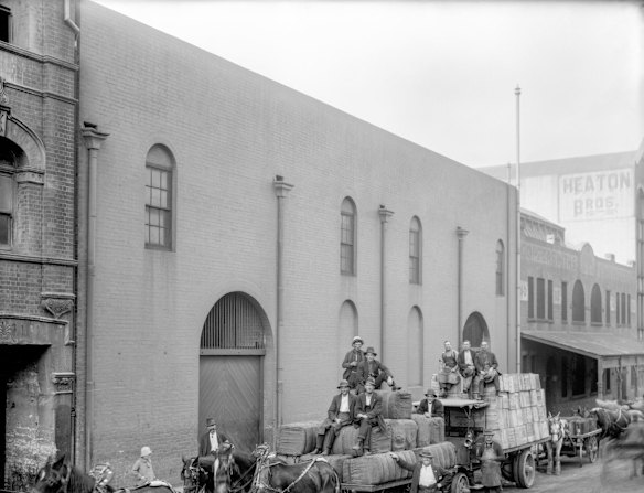 104-108 Sussex Street, 1920. Men sit on top of horse-drawn drays lined up outside the John Keep warehouse on Sussex Street. The drays are piled high with bales and tea chests.