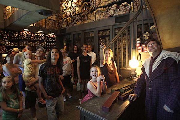At Ollivander's Wand Shop helps visitors pick out a magic wand at The Wizarding World of Harry Potter at Universal Orlando theme park.