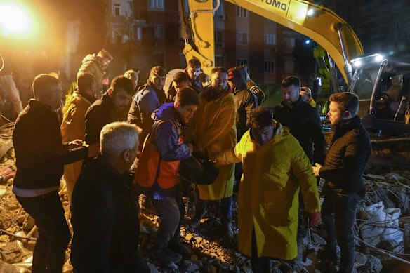 Emergency team members carry the body of a person found in the rubble of a destroyed building in Adana, Turkey.