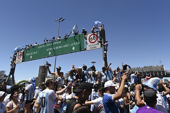 Argentine soccer fans climb on highway signs for a homecoming parade for the Argentine soccer team that won the World Cup tournament in Buenos Aires, Argentina.