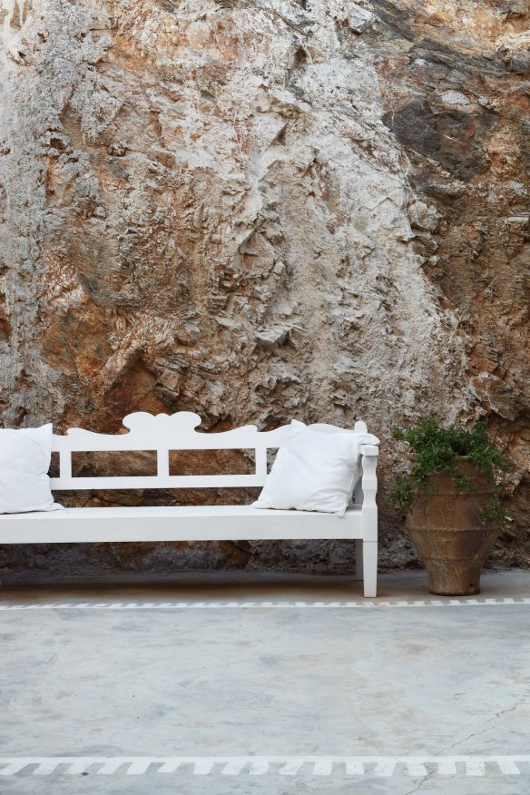 A painted bench on the terrace contrasts with the raw rock behind.