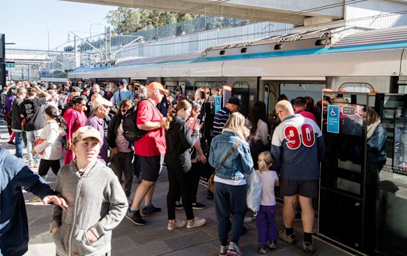 Crowds board the trains through glass gates.