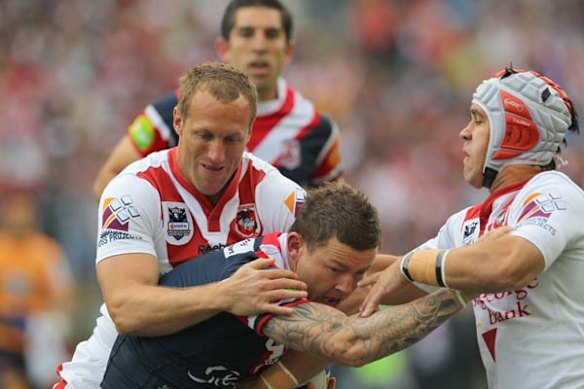 The Dragons Mark Gasnier and Jamie Soward attemp to take down Rooster Todd Carney.