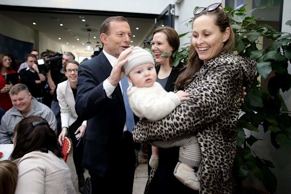 Opposition Leader Tony Abbott and Liberal MP Kelly O'Dwyer meet with Amelia Taylor and 5-month-old Thomas, during his visit to a cafe in Malvern, Victoria.
