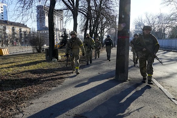 Ukrainian soldiers patrol an area not far from burning military trucks in a street in Kyiv. Russian troops pushed toward Ukraine's capital on Saturday, and street fighting broke out as city officials urged residents to take shelter.