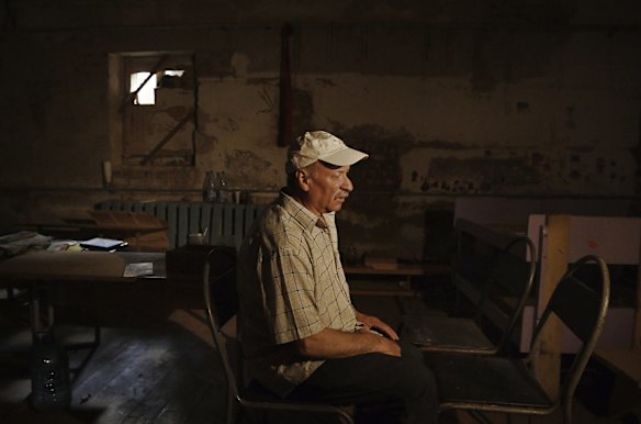 Ivan, 62, sits in his chair, one of four that were his family's area while being held in the basement of a school for 25 days.