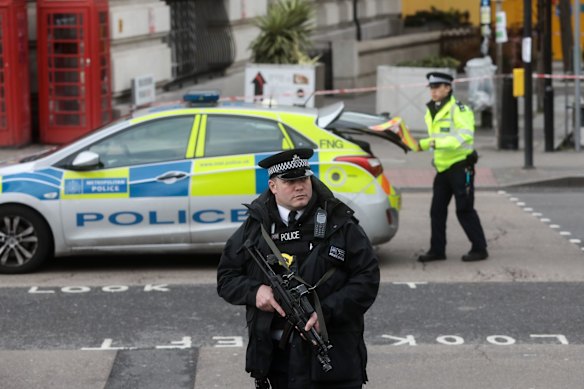An armed British police officer stands at a police cordon near Westminster Bridge and the Houses of Parliament in central London.