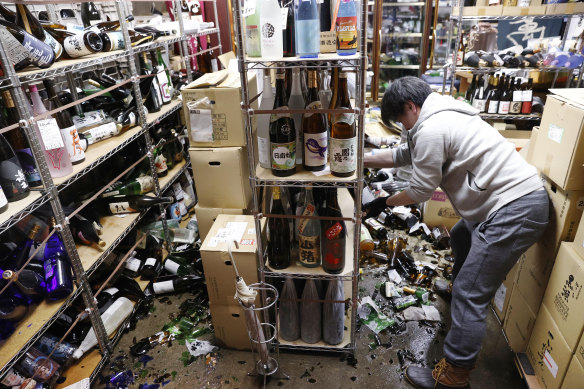 A liquor shop’s manager clears the damaged bottles following an earthquake in Fukushima.