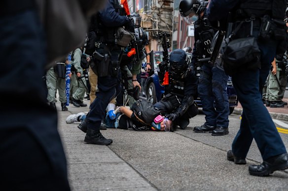 A pro-democracy supporter is detained by riot police during an anti-government rally.