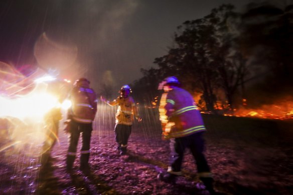 Firefighter Mikaela Kremer from Glenbrook-Lapstone does a dance to celebrate the rain suddenly falling just as they were responding to spotting from Green Wattle Creek bushfire west of Bargo off Tylers Road, on Saturday 21 December 2019. 