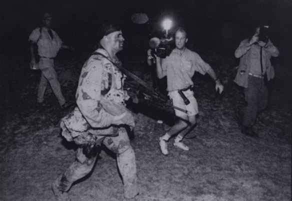 Braving the warring clans of reporters, photographers and anchormen, US forces storm the beaches at Mogadishu.