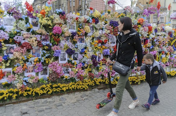Passersby contemplate a wall of artificial flowers set up by the US-based Wall of Flowers Foundation in memory of the victims of Russia's invasion, in Ukraine's western city of Lviv.