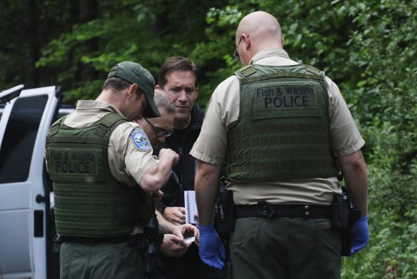 Washington State Fish and Wildlife Police confer with an individual from the King County Medical Examiner's Office and a King County Sheriff's deputy on a remote gravel road following a fatal cougar attack on Saturday. 