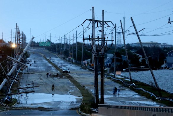 Downed power lines and a battered road is what superstorm Sandy left behind as people walk off the flooded Seaside Heights island