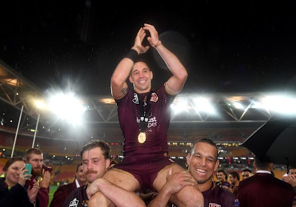 Billy Slater of the Maroons is chaired from the field by Cameron Munster (left) and Will Chambers.