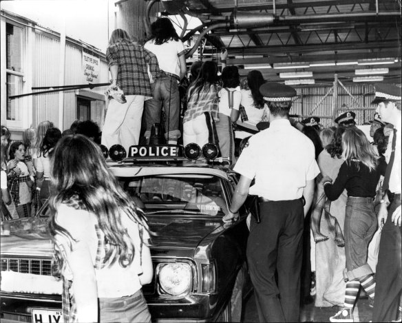 Fans of the Bay City Rollers stand on a police car for a glimpse of their idols. December 4, 1975. 