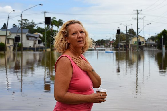 An emotional resident cannot return to her damaged home as she stands at the waters edge of the flooded streets of Lismore.