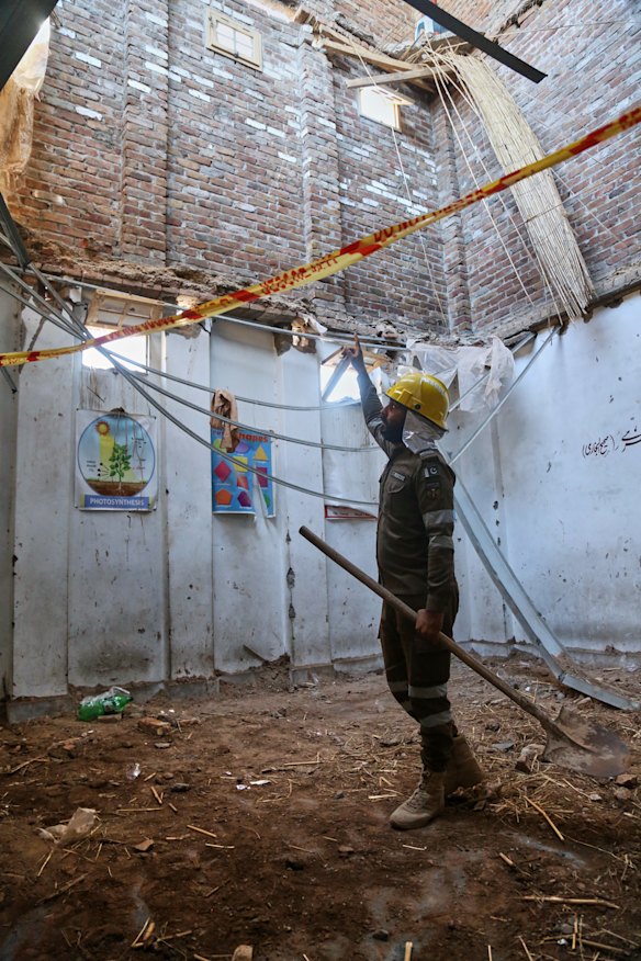 A rescue worker gestures toward roof as he searches through the rubble.
