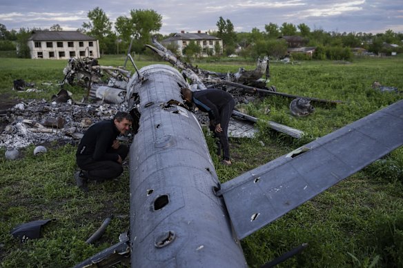 Oleksiy Polyakov (right) and Roman Voitko check the remains of a destroyed Russian helicopter in a field in the village of Malaya Rohan, Kharkiv.