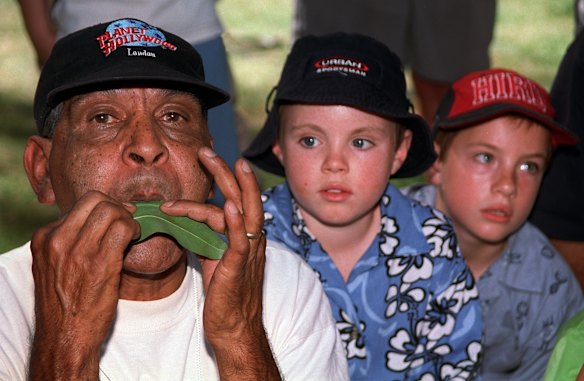 Herb Patten teaches enthusiastic listeners the art of playing a gum leaf, on his right are Jamie Curran and Luke Cauchi at Moomba in Treasury Gardens, 2002.