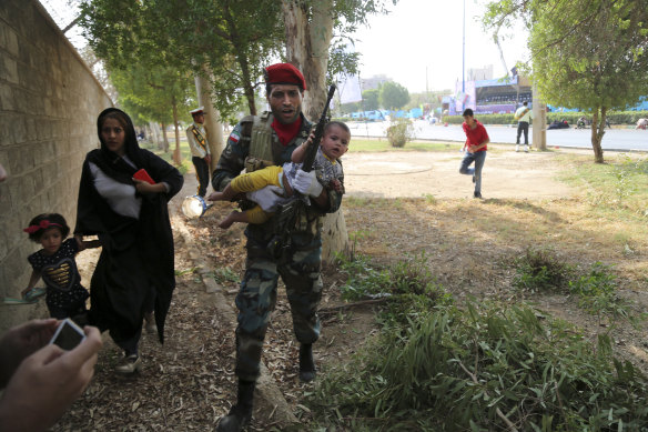 Iranian army member carries a child away from the shooting scene. 